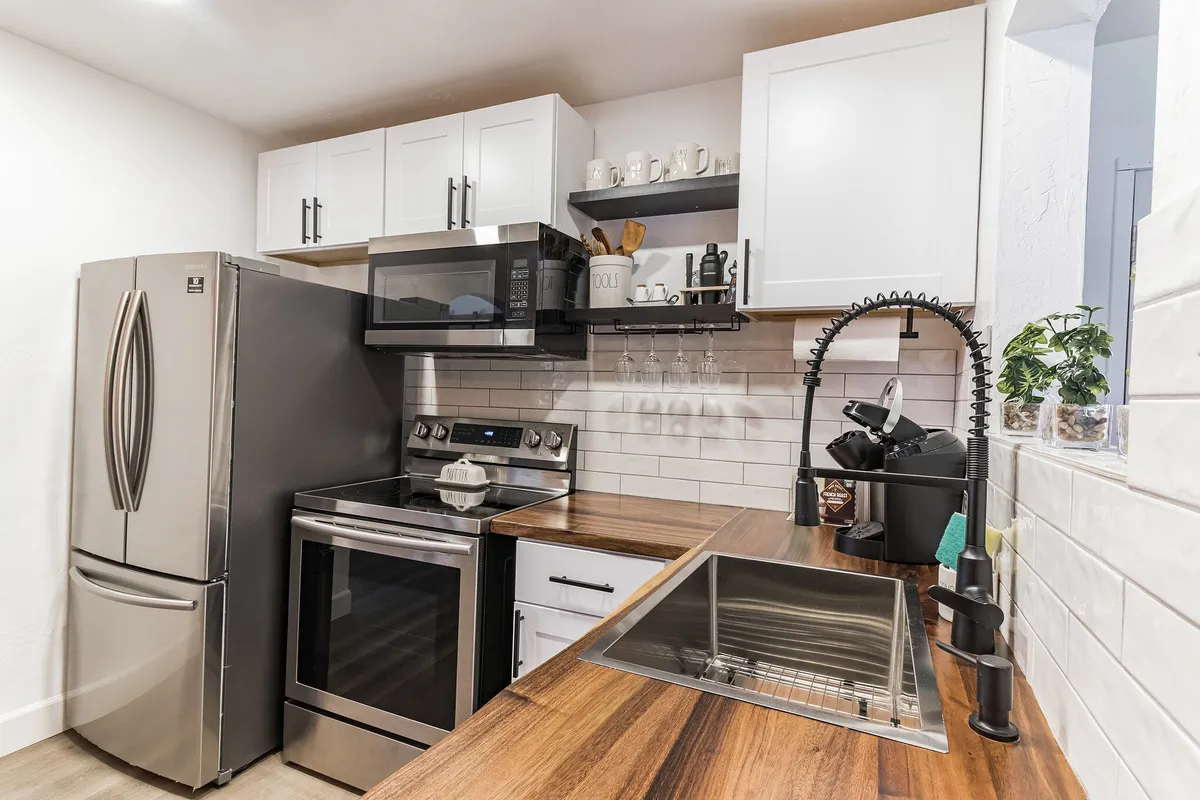 A cozy and functional kitchen featuring stainless steel appliances, a wooden countertop, and a modern sink. The scene suggests the kitchen is ready for cooking, entertaining, or family gatherings.