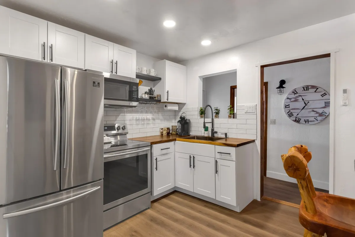 A functional and stylish kitchen equipped with stainless steel appliances, a wooden countertop, and white cabinetry. The space is designed for cooking, baking, and enjoying coffee with friends or family.